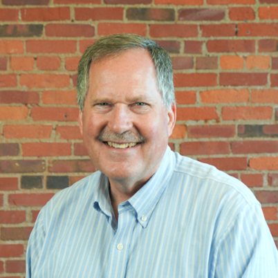 Headshot of Dan Rice on a brick background