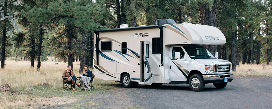 Couple sitting outside their camper in the forest