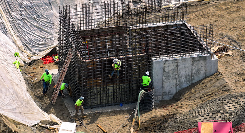 Construction workers surrounding a concrete and rebar structure