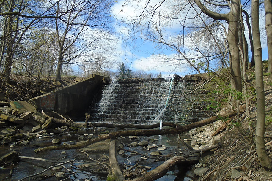 Water flowing down a dam built of sandstone with a shallow river running in the front.