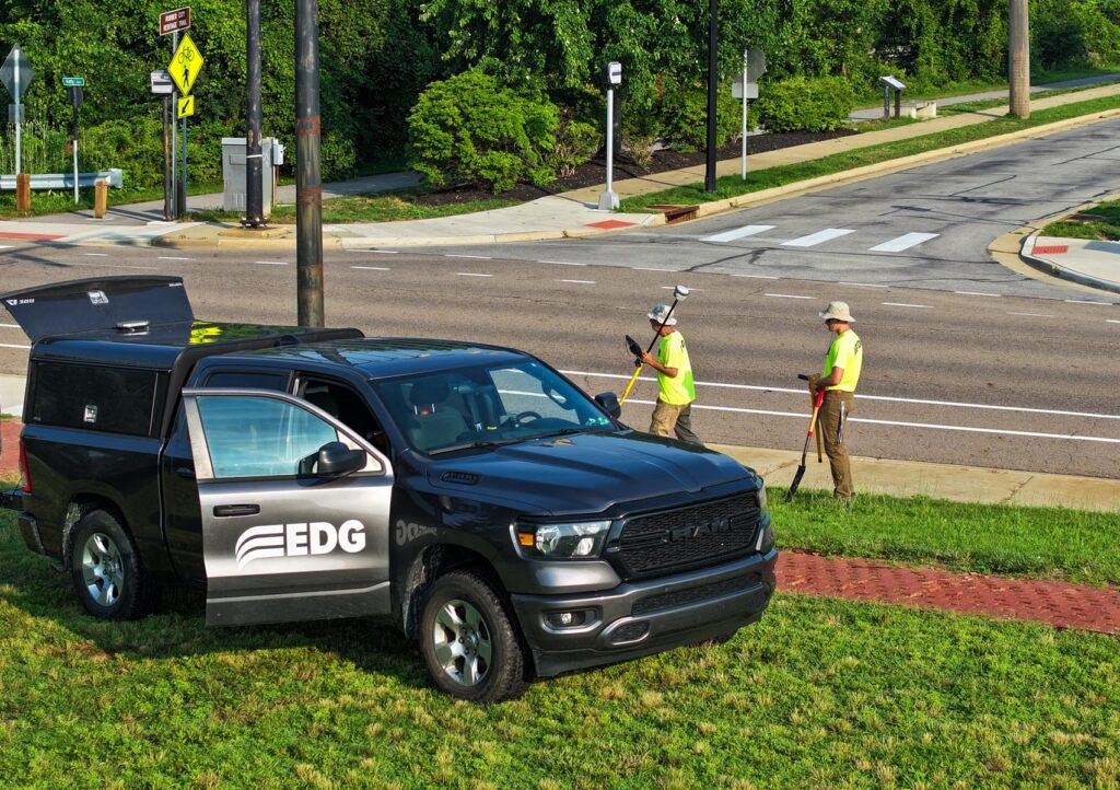 Two men in neon EDG shirts working by a road