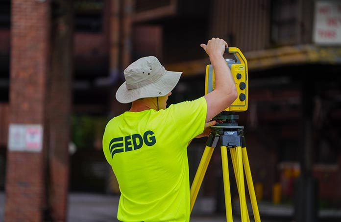Person wearing a neon yellow EDG shirt, working on a surveying tool