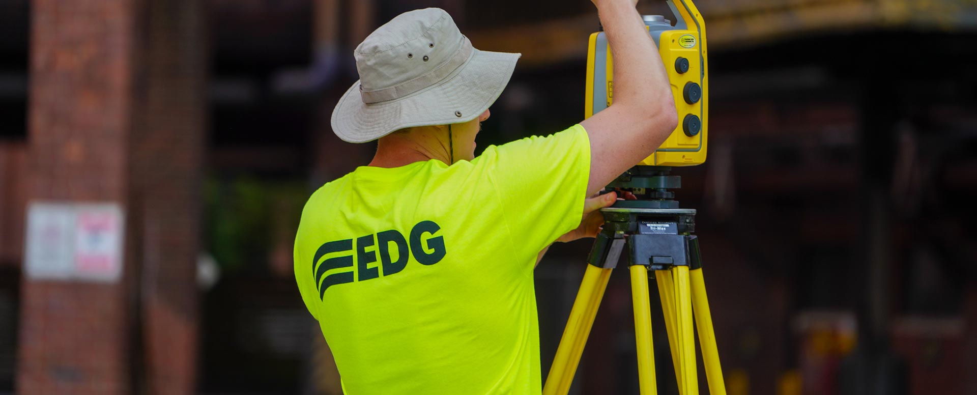 Person wearing a neon yellow EDG shirt, working on a surveying tool