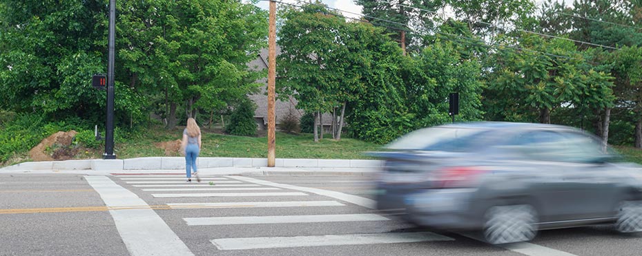 Car driving through an intersection as a pedestrian crosses the cross walk