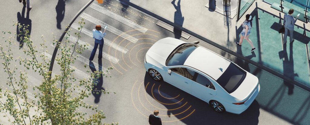 Aerial view of a city intersection with pedestrians on their phones, crossing in the middle of the road, and a car with sensors on the front and driver sides.
