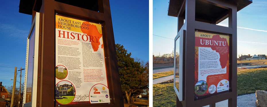 Two illuminated outdoor informational signs at the East End Neighborhood House—one titled “History” and the other “Ubuntu”—displaying text and images along a landscaped pathway at dusk.